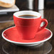 A close up of a red CAC Venice espresso cup on a red saucer.