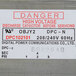 A white sticker with red text reading "Danger High Voltage" on a power supply.