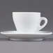 A close-up of a CAC white espresso cup and saucer on a white surface.