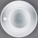 A CAC white espresso cup and saucer on a white surface.