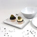 A white rectangular tray with black trim holding cupcakes and a white bowl with a black rim on the side.
