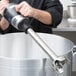 A hand using a Waring stainless steel shaft on a commercial immersion blender.