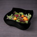 An Elite Global Solutions black melamine bowl filled with salad on a counter.