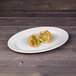 An Elite Global Solutions white oval melamine platter with cut up oranges on it.