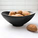 An Elite Global Solutions black melamine oval bowl filled with potatoes.