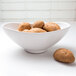 An Elite Global Solutions white melamine oval bowl filled with potatoes on a table.