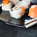 A plate of sushi with chopsticks on a black Elite Global Solutions organic edge plate.