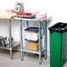An Advance Tabco stainless steel work table with a galvanized undershelf on a kitchen counter.