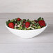 A white Elite Global Solutions Moderne oblong bowl filled with strawberries and kale salad.