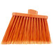 A close up of a Carlisle medium duty broom head with orange flagged bristles.