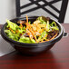 A bowl of salad with carrots and chicken in a Fineline black plastic bowl.