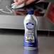 A hand using Bar Keepers Friend Liquid Cooktop Cleaner on a stove.