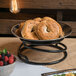 A black metal Elite Global Solutions SSDR4-RC steel stand with bagels and a bowl of berries on a table.