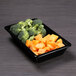 A black rectangular melamine bowl with broccoli and carrots.