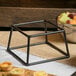 A metal square stand with fruit and bread on it.