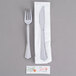 A white napkin wrapped around a fork and knife with a silver handle.