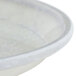 A Cambro round fiberglass tray with a white antique parchment design.