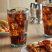 A GET Bahama plastic tumbler filled with ice tea on a table with a slice of pizza.