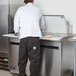 A man in a white shirt standing next to an Arctic Air 2 door mega top sandwich prep table in a commercial kitchen.