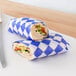 A sandwich wrapped in blue and white Choice deli wrap paper.