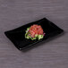 An Elite Global Solutions black rectangular wave platter with raw tuna on a table.