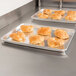 A Vollrath Wear-Ever aluminum bun sheet pan with pastries on it on a counter.
