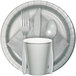 A white table covered with a Creative Converting Shimmering Silver table cover with silverware and a white cup.