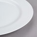 A close up of a 10 Strawberry Street Classic White Porcelain Charger Plate with a rim.