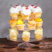 A clear plastic Fineline cake stand with three tiers holding cupcakes.