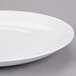 A close up of a 10 Strawberry Street Royal Coupe white porcelain plate with a rim on a gray surface.