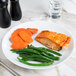 A 10 Strawberry Street white porcelain plate with salmon, green beans, and carrots on a table.