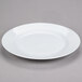 A 10 Strawberry Street Royal White porcelain charger plate with a rim on a gray surface.