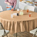 A table with a Creative Converting Glittering Gold OctyRound table cover and glasses of orange juice.