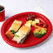 A Creative Converting Classic Red oval paper platter with a sandwich and fruit on it.