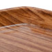 A close up of a brown wood Cambro trapezoid tray.