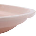 A light peach Cambro oval tray with a white rim on a counter.