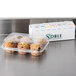 A plastic container of muffins next to a Noble Products 7-Slot Dispenser with 7 rolls of food rotation labels.
