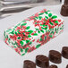 A 1/4 lb. Poinsettia holiday candy box on a counter filled with chocolates.