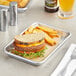 A Choice aluminum bun pan with a sandwich and fries on it.