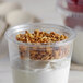 A clear Fabri-Kal plastic cup filled with yogurt and granola.