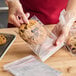 A hand in a plastic glove holding a cookie in a LK Packaging plastic resealable bag.
