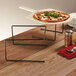 An American Metalcraft black universal pizza stand with a pizza on a table.