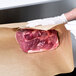 A person in gloves holding a piece of meat in Bagcraft Packaging EcoCraft Freezer Paper.