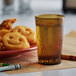 A plate of fried chicken and a GET Amber plastic tumbler filled with liquid.
