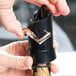 A hand using a Vacu Vin black and silver champagne saver to open a bottle of wine.