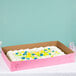 A Baker's Mark full sheet cake in a pink box with frosting and flowers.