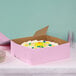 A close-up of a pink cake in a 14" x 14" x 5" pink bakery box.