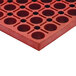 A red rubber mat with holes in it.