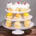 A Fineline white two-piece cake stand holding cupcakes.
