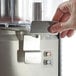 A hand pressing a push button on the Omega OSD20 Double 3 Gallon Bowl Refrigerated Beverage Dispenser.